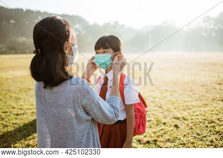 Mother Help Her Daughter To Put On The Mask Before Going To School