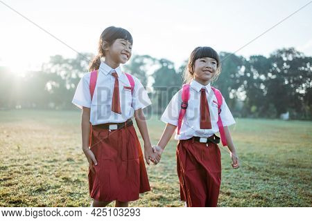 Happy Female Asian Primary School Student Walk Together