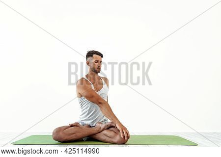 Male Yoga Maditates In Classical Pose In Studio Over White Background