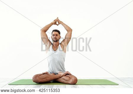Male Yoga Maditates In Classical Pose In Studio Over White Background