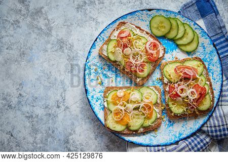 Plate with toasts with cucomber, tomatoes and crumbled feta and radish sprouts