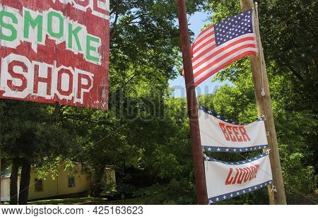 Smoke Shop Sign Next To Beer And Liquor Sign With American Flag. Rural Texas Scenery. Small Town Tex