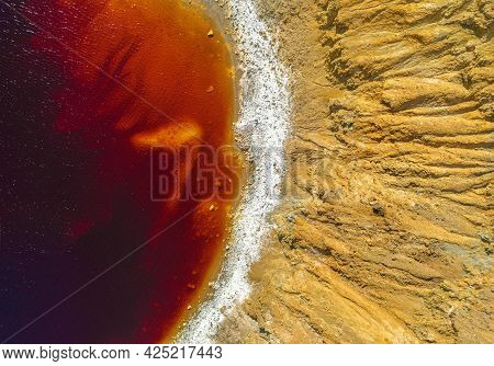 Shore Of Toxic Red Lake In Abandoned Open Pit Copper Mine. Its Unusual Color Is The Result Of The Py
