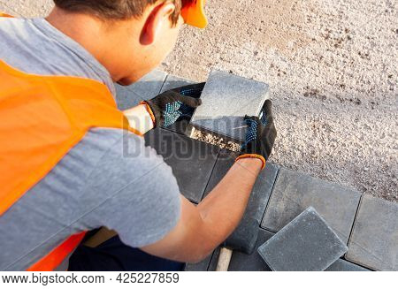 Worker lining paving slabs path