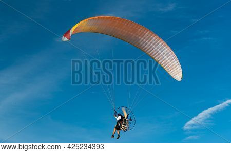 The People Was Playing A Paramotor Which A Small Aircraft, Flying On Bule Sky Beautiful Nature Backg