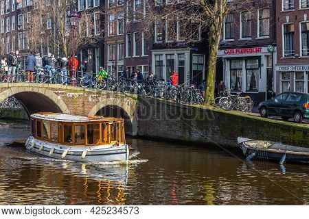 Amsterdam, Netherlands -12 March 2016: Boats On The Amstel Canal And People Walking Around. Bridge O
