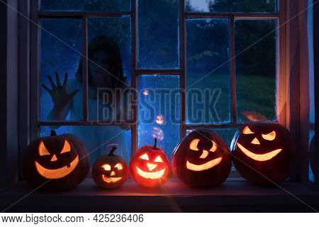 Halloween Pumpins On Windowsill With Ghost Outside  Window