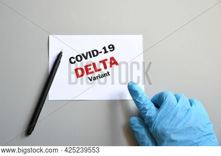 Doctor Hand With Blue Glove With White Card And Text Covid-19 Delta Variant And Pen. Medical And Cov