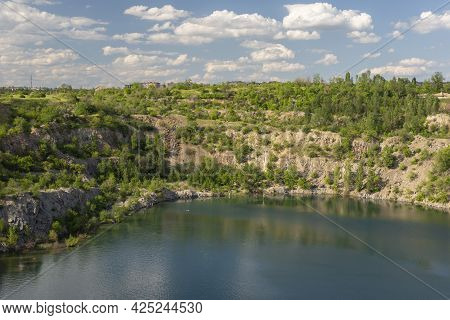 Landscape Of A Granite Quarry Against A Summer Cloudy Sky.