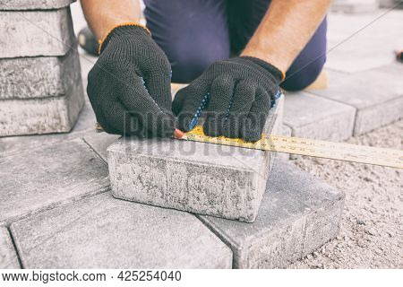 Worker lining paving slabs path