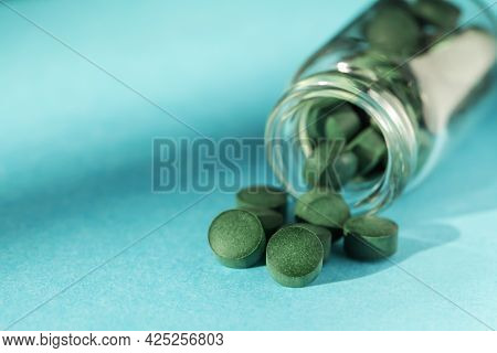 Spirulina Pills In Glass Jars On Blue Background. Antioxidant Nutrition. Bio-energy, Biofuel, Energy