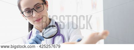 Woman Podiatrist Examining Heel Of Patient Using Magnifying Glass