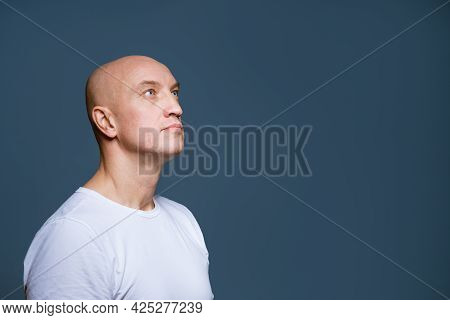 Bald Man Looking To The Side On A Blue Background In A White T-shirt. Caucasian Guy Looks To The Sid