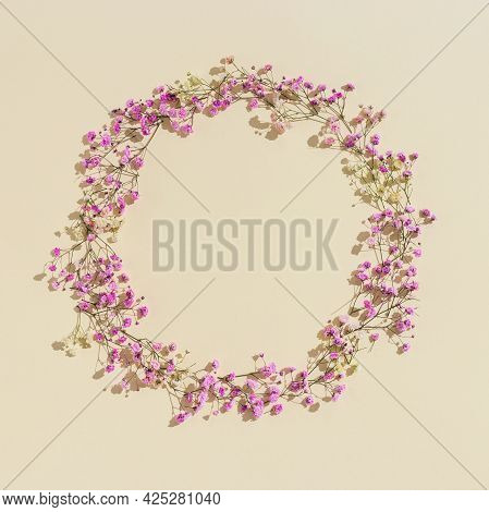 Minimal Natural Round Frame Made With Small Pink Flowers On Beige Colored Background. Floral Visuals