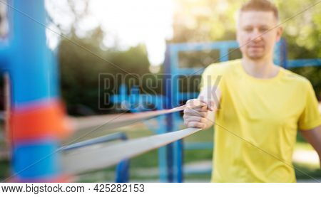 Sportsman exercising with elastic rubber band, close up view on band