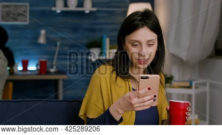 Beautiful Woman Holding Phone In Hand Reading Message On Internet Resting On Cozy Couch Late At Nigh