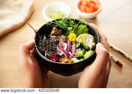 A Man Holds A Poke Salad With Beef In A Bowl In His Hands. Ingredients Beef, Nameko Mushrooms, Cherr