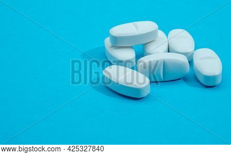 Pills On A Blue Background. White Pills Lie On A Blue Background. Close Up.