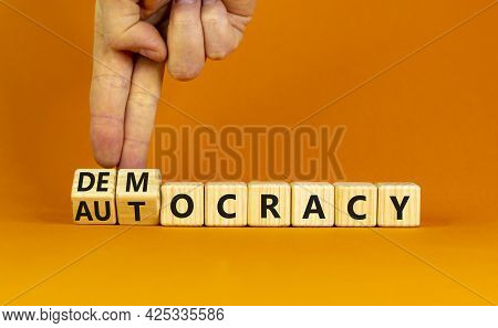 Democracy Or Autocracy Symbol. Businessman Turns Wooden Cubes And Changes The Word Autocracy To Demo