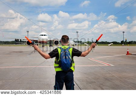 The Traffic Controller At The Airport Shows The Semaphore With Sticks To The Pilot Of The Plane Wher