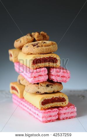 Nærbillede af en stak af diverse cookies med en lys til mørk baggrund. Lodret format med overfladisk