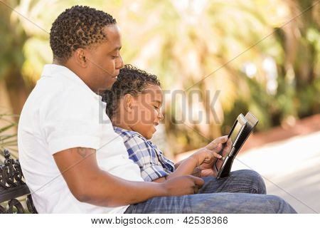 Heureux African American père et fils de Race mixte ayant amusant à l'aide de Touch Pad ordinateur tablette à l'extérieur.