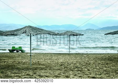Panorama Of A Beach With Parasol Sun Umbrella During A Cloudy Rainy Afternoon On The Prespa Lake On 