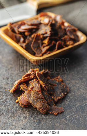 Sliced beef jerky. Dried beef meat on old kitchen table.