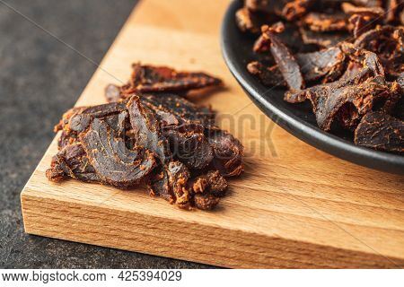 Sliced beef jerky. Dried beef meat on cutting board.