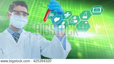 Digital medical icons against caucasian male doctor wearing face mask holding a test tube. medical research and science technology concept