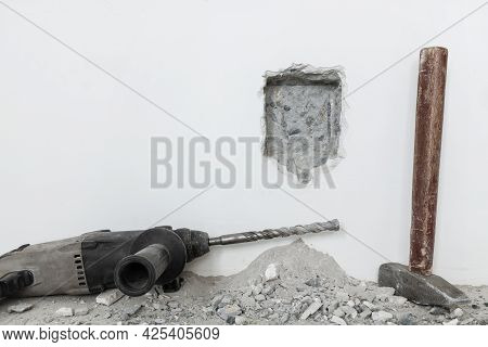 Slotted Hole With A Pre-drill And Hammer In The White Wall For Recessed Socket. Construction And Ren