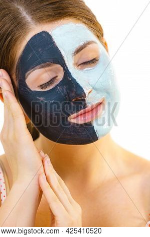 Woman With Clay Carbo Black Mask On Half Face And White Mud On Second Half. Girl Taking Care Of Oily
