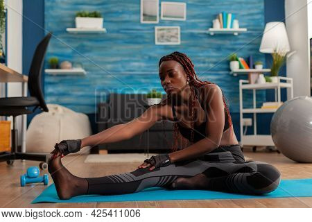 Fitt Black Woman Sitting On Yoga Mat Doing Stretching Leg Routin On The Floor In Home Living Room, H