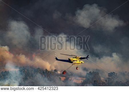 Two Helicopters With Bambi Bucket Team Working On Fire Extinction