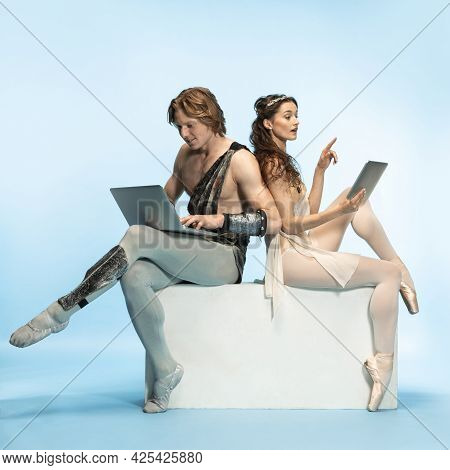 Tablet, Laptop, Digital. Young Couple Of Ballet Dancers In Ancient Rome Costums At Blue Studio.