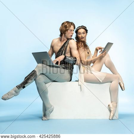 Tablet, Laptop, Digital. Young Couple Of Ballet Dancers In Ancient Rome Costums At Blue Studio.