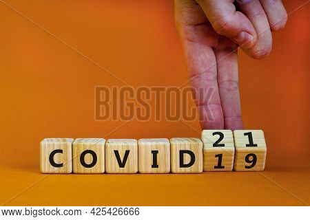 Symbol Of Covid-19 Pandemic In 2021 Year. Businessman Turns Wooden Cubes And Changes Words 'covid-19