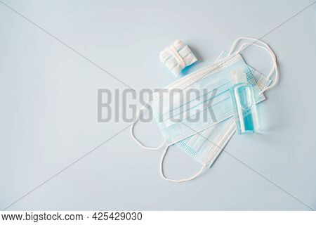 Bottle Of Alcohol Gel On Blue Disposable Face Mask And Used Mask, Necessary For New Normal Lifestyle
