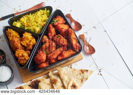 Spicy indian fried chicken served with curry vegetable rice, onion bhajia, naan bread