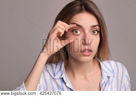 Woman Checking Her Health Condition On Grey Background. Yellow Eyes As Symptom Of Problems With Live