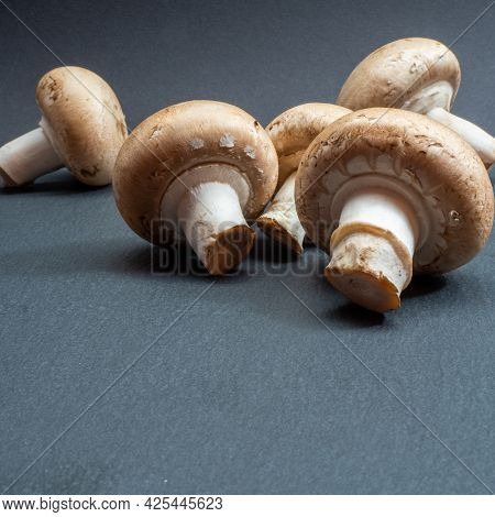 Champignons On A Black Textured Board, Close Up.