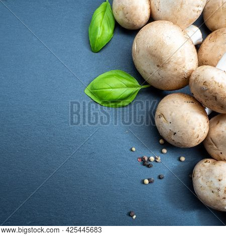 Champignons With Spices On A Black Textured Board, Close Up.