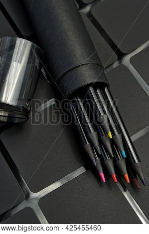 Set Of Colored Pencils In A Round Cardboard Case On A Dark Background.