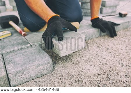 Worker lining paving slabs path