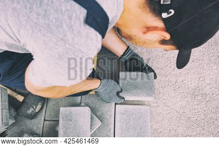 Worker lining paving slabs path