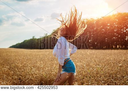 Beautiful Young Woman In Wheat Field. Cute Brunette Girl Of Caucasian Appearance In Casual Clothes I