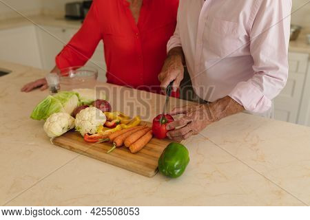 Mid section of senior caucasian couple cooking together in kitchen. retreat, retirement and happy senior lifestyle concept.