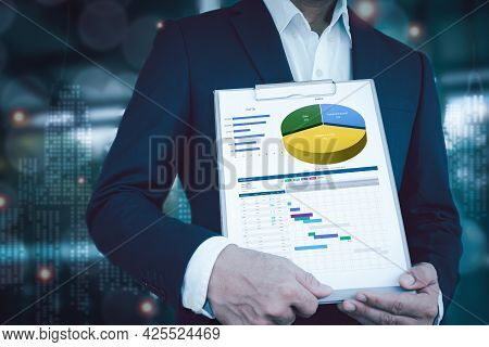 Man Wearing Suit, Holding The Files With Graphs Of Savings Data And Investment Details. The Backgrou