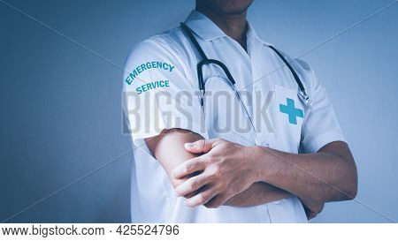 Professional Doctor With A Stethoscope Is Standing With Crossed Arms In A Clinic. Young Doctors At W