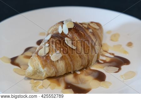 Baked Croissant With Caramel And Syrup On White Plate For Homemade Breakfast With Almond
